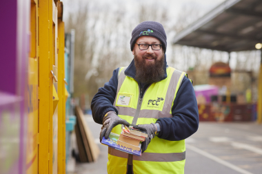 staff member on HWRC site holding some books for reuse