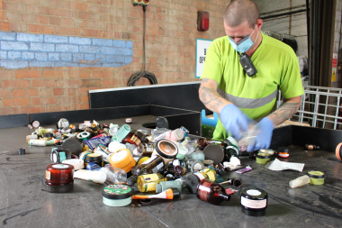 operative with mask and gloves sorting cosmetics at a large table